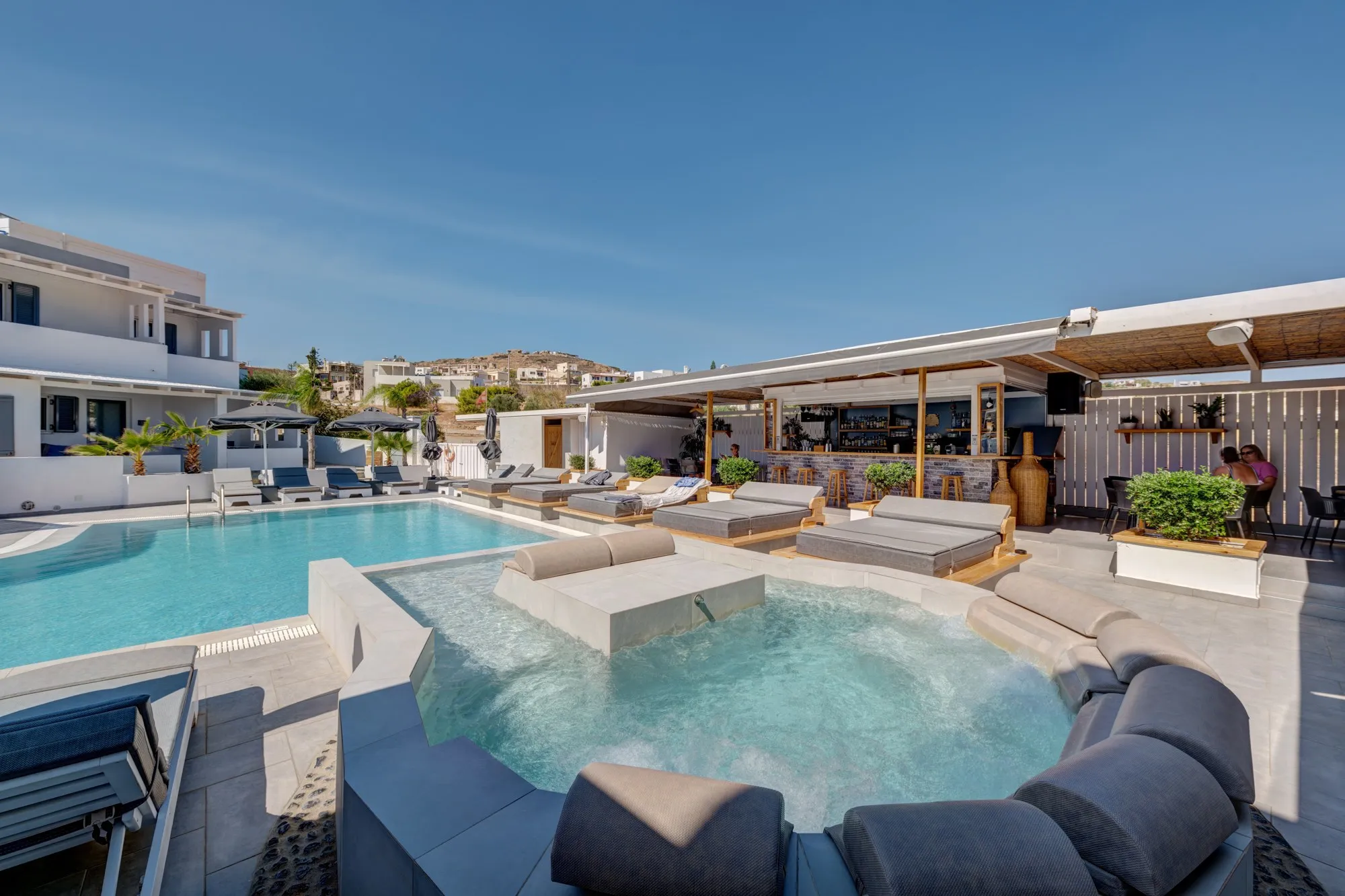 The hydromassage ringed by cushioned seating, beside the pool and the pool bar