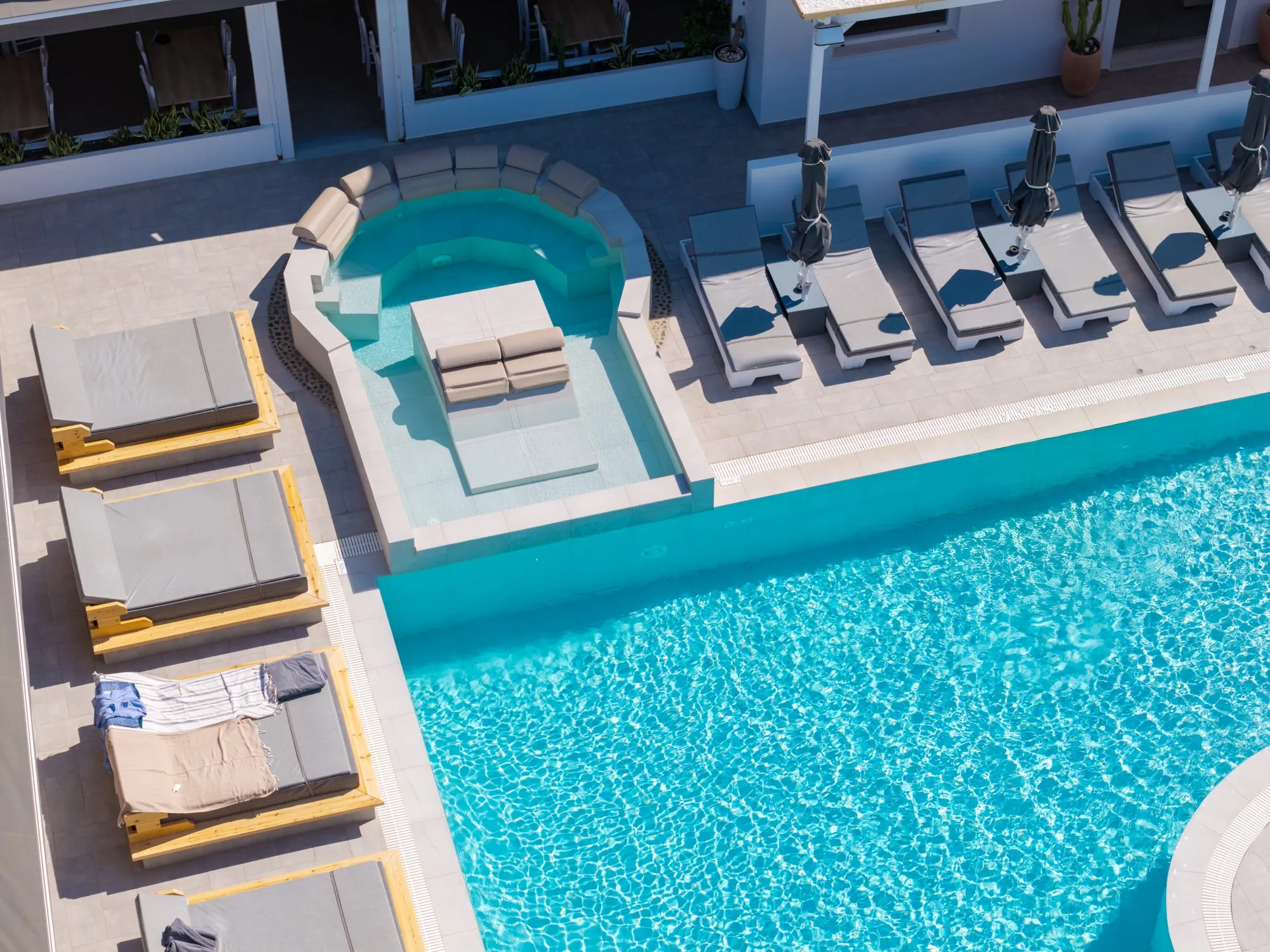 Daybeds and sun loungers along the pool beside the hydromassage, seen from above