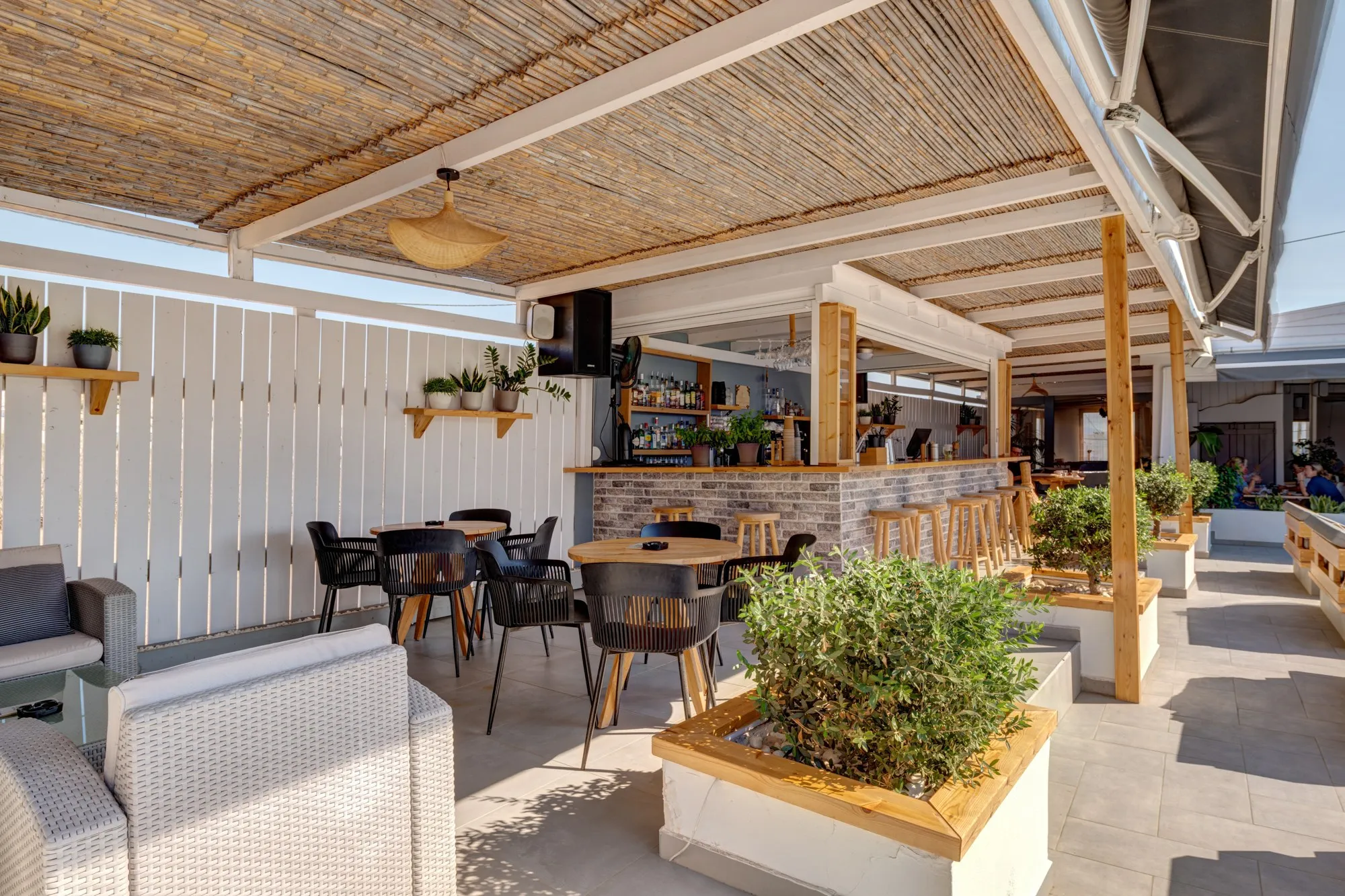 The pool bar under its reed roof, with the counter and stools, tables and planters