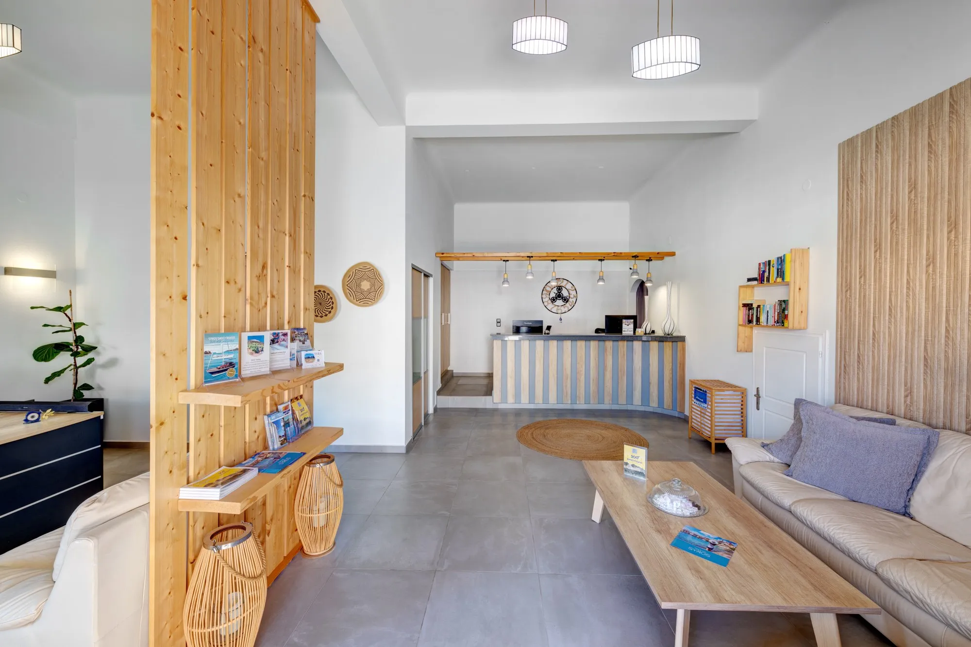 The reception desk at the end of a bright lounge with a sofa, a wooden coffee table and island guides