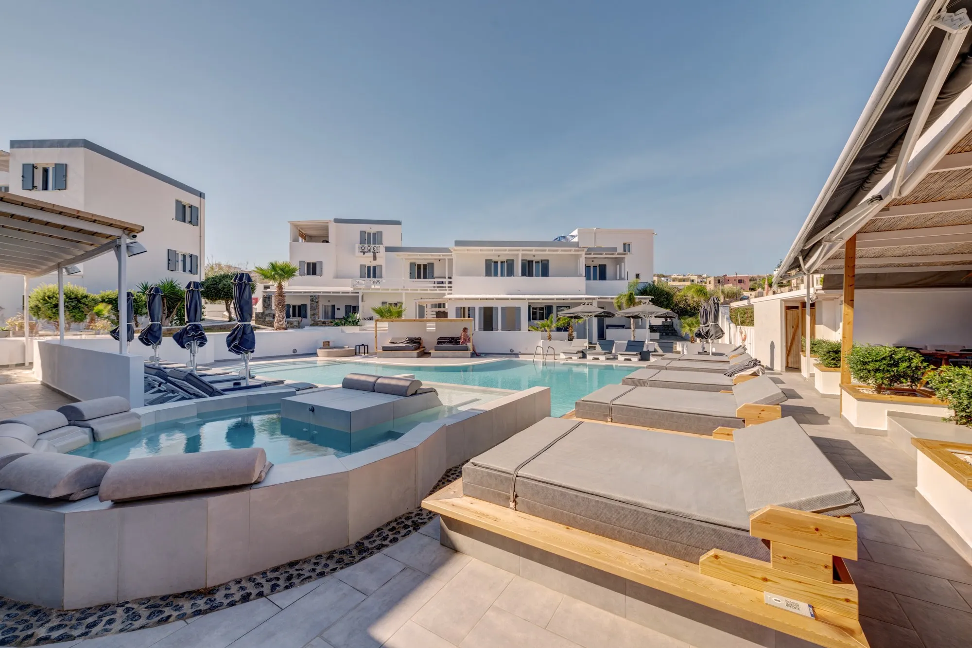 Daybeds on wooden platforms along the pool, beside the hydromassage